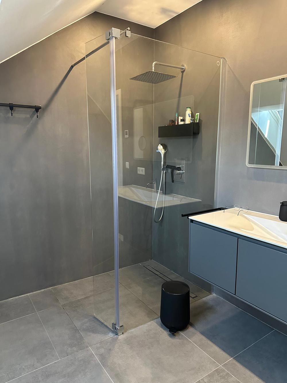 Modernes graues Bad mit Glasdusche und schwarzer Regendusche, sauber