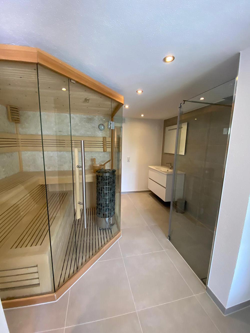 Modernes Bad mit Glasdusche und Sauna in Grau und Holz, helles Licht